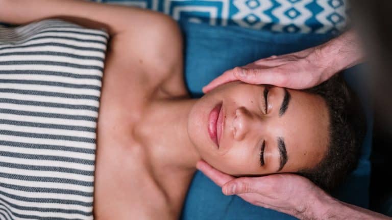 Person receiving a facial massage, relaxing with eyes closed on a spa table.